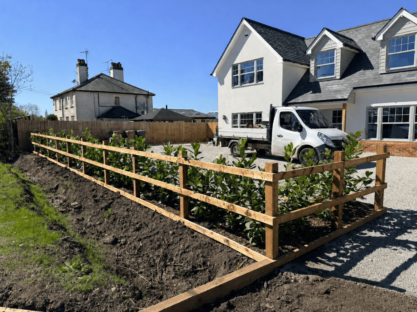 Post-and-rail fencing with laurel hedging and TimBear Builds truck on a driveway in Essex