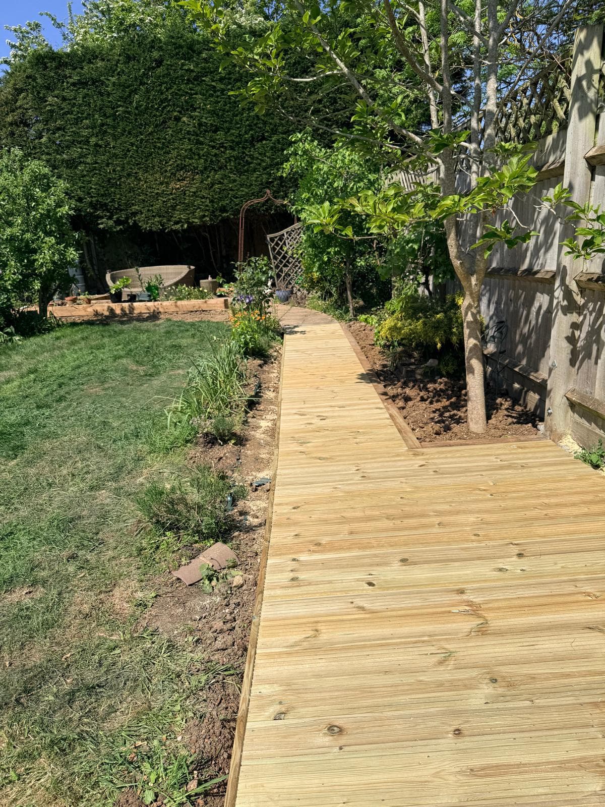 Timber decking walkway running alongside a garden border